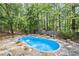 Kidney shaped pool surrounded by a stone patio and a fenced yard with mature trees at 24 Picketts Mill Pl, Acworth, GA 30101