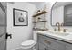 Bright bathroom featuring a vanity with marble countertop, grey cabinetry, and open shelving for storage and decorative display at 3182 Wakefield Dr, Decatur, GA 30034