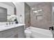 Modern bathroom features a gray vanity with marble countertop, arched mirror, and a tub-shower combo with gray tiling at 3182 Wakefield Dr, Decatur, GA 30034