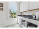 Bright laundry room with white cabinets, patterned floor tiles, and natural light from a large window at 260 Jasmine Garden Way, Alpharetta, GA 30009