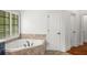 Bright bathroom showcases a luxurious soaking tub with tile surround and a window with natural light at 201 Hunley Ct, Alpharetta, GA 30005