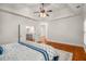 Bedroom featuring hardwood floors, tray ceiling, ceiling fan, and an open door to the hall and stairs at 201 Hunley Ct, Alpharetta, GA 30005