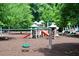 A playground with multiple slides and swings is surrounded by lush green trees and soft mulch at 201 Hunley Ct, Alpharetta, GA 30005