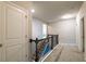 Upstairs hallway with neutral carpet and a dark wood railing staircase leading to the lower level at 590 Birkdale Dr, Fairburn, GA 30213
