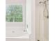 This bathroom boasts a bright tub and a shower head with a nearby window at 6230 Lillie Lane, Cumming, GA 30040