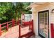 View of the home's red deck with a greenhouse and back door entrance, surrounded by lush trees at 6416 Chestnut Glen Dr, Norcross, GA 30071