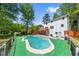 Backyard pool with surrounding green turf, wooden deck, and white home exterior surrounded by mature trees at 664 Somerset Dr, Lawrenceville, GA 30046