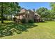 View of the brick home's backyard featuring a spacious lawn and a wooden deck, perfect for outdoor enjoyment at 1551 Pharrs Rd., Snellville, GA 30078