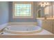 Well-lit bathroom with a jacuzzi-style bathtub and stained glass window at 1551 Pharrs Rd., Snellville, GA 30078