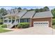 Brick home featuring an attached two-car garage and a covered front porch with white railing and blue shutters at 2949 Lake Spivey Pkwy, Jonesboro, GA 30236