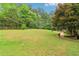 Sprawling backyard featuring lush green grass, mature trees, split rail fence, and stone pathway with garden beds at 5250 Aubrey Ln, Cumming, GA 30028