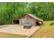 Exterior of the rustic wooden barn with an attached carport and an outdoor hot tub adjacent to green trees at 5250 Aubrey Ln, Cumming, GA 30028