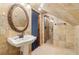 Tiled bathroom featuring a pedestal sink, decorative mirror, and glass-enclosed shower at 5250 Aubrey Ln, Cumming, GA 30028