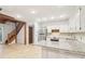 Bright kitchen with white cabinets, stainless steel appliances, granite countertops, and a staircase in view at 5250 Aubrey Ln, Cumming, GA 30028