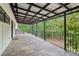 Exterior view of the stone tile patio with covered awning and wrought iron railing with lush greenery in the background at 5250 Aubrey Ln, Cumming, GA 30028