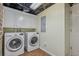 Functional laundry room featuring white washer/dryer set and overhead cabinets for storage at 933 N Highland Ne Ave, Atlanta, GA 30306