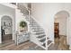 Elegant foyer featuring a staircase with decorative wrought iron railing and an arched doorway into the dining room at 1039 Avery Creek Dr, Woodstock, GA 30188