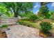 Relax in the serene backyard with a stone patio, built-in bench, lush greenery, and wooden privacy fence at 1492 Frazier Rd, Decatur, GA 30033