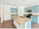 A bright kitchen features an island, stainless steel appliances, granite countertops and beautiful blue cabinetry at 4615 Elmwood Trl, Cumming, GA 30028