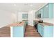 A wide shot of a bright kitchen with an island and stainless steel appliances, granite countertops and blue cabinetry at 4615 Elmwood Trl, Cumming, GA 30028