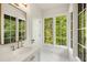 This bright bathroom includes gold fixtures, marble counters, and views of green trees at 1026 Reeder Cir, Atlanta, GA 30306