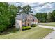 Aerial front view of a brick two-story home with black shutters, manicured lawn, and three car garage at 4290 Grand Teton Pkwy, Suwanee, GA 30024
