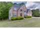 View of a brick house on a green lot with trimmed shrubs, side yard, and a two-car garage at 4290 Grand Teton Pkwy, Suwanee, GA 30024