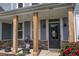 Close-up of the front porch featuring wood pillars, a decorative statue, and vibrant red flowers at 162 Greenbrier Way, Canton, GA 30114