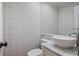 Stylish powder room with patterned wallpaper, pedestal sink, and decorative mirror at 25 Ivy Gates Ne, Atlanta, GA 30342