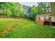 View of the expansive backyard featuring mature trees, partial fencing, and a small deck adjacent to the home at 5105 Davidson Ne Rd, Marietta, GA 30068