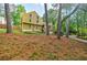 View of a two-story house with yellow siding and stone accents, surrounded by lush greenery and trees at 5105 Davidson Ne Rd, Marietta, GA 30068