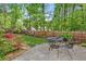 A backyard patio features a dining set, manicured lawn, and a wooden fence that is lined with lush trees and landscaping at 1824 Mallard Lake Dr, Marietta, GA 30068