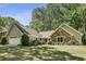 View of single Gathering home with manicured lawn, mature trees, attractive stone and siding exterior at 1390 Barclay Dr, Lawrenceville, GA 30043