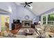 Living room featuring vaulted ceiling, skylight, ceiling fan, stone fireplace, and backyard views at 1390 Barclay Dr, Lawrenceville, GA 30043