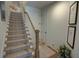 Carpeted stairway with a wooden handrail, white risers and hardwood flooring at the bottom of the stairs at 14 Lochurst Ln # 15, Roswell, GA 30076