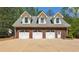 Three-car garage exterior with white doors, brick facade, and dormer windows, providing a stylish and functional space at 190 Ward Rd, Ellenwood, GA 30294