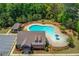 Aerial view of a large, uniquely shaped community pool, clubhouse and ample green space surrounded by trees at 3049 Ivy Crossing Dr, Buford, GA 30519