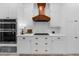 Modern kitchen with white cabinets, a wooden range hood, stainless steel appliances, and elegant gold hardware at 230 Bristolstone Ct, Alpharetta, GA 30005