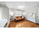A bright living room with wood floors, a brown leather couch, white walls, and natural light from the window at 230 Bristolstone Ct, Alpharetta, GA 30005