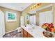 Well-lit bathroom featuring a single sink, toilet, decorative flowers, and a large mirror at 745 Beaver Pond Trl, Fairburn, GA 30213