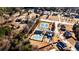 A lovely aerial view of a pool, two tennis courts, mature trees, and neighborhood homes in a residential setting at 5447 Stirrup Way, Powder Springs, GA 30127