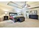 A well-lit bedroom featuring a tray ceiling, carpet flooring, a large bed, and nightstands at 5447 Stirrup Way, Powder Springs, GA 30127