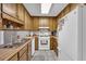 Galley kitchen featuring wood cabinetry, white appliances, tile flooring, and a stainless steel sink at 865 Turner Dr, Lawrenceville, GA 30046