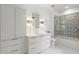 Modern bathroom featuring white cabinets and drawers, shower over tub and neutral-toned tiles at 5260 Long Island Nw Dr, Atlanta, GA 30327
