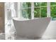 Elegant freestanding bathtub positioned in front of a large window with natural light and greenery at 5260 Long Island Nw Dr, Atlanta, GA 30327