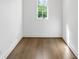 A view of an empty room with a natural wood floor and white trim with a bright window view at 5260 Long Island Nw Dr, Atlanta, GA 30327
