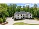 A luxurious white home boasting a circular driveway, basketball court, and lush greenery at 5260 Long Island Nw Dr, Atlanta, GA 30327