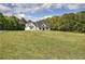 Expansive lawn surrounds this modern farmhouse, creating a picturesque setting with mature trees on the horizon at 613 Nebo Rd, Dallas, GA 30157