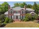 Elegant brick home featuring a manicured lawn, balanced landscaping, and a welcoming covered front porch at 225 Farmbrooke Ct, Sandy Springs, GA 30350