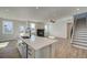 Open living space with a bright kitchen, island with sink, fireplace, and a staircase at 4730 Montane St, Cumming, GA 30028